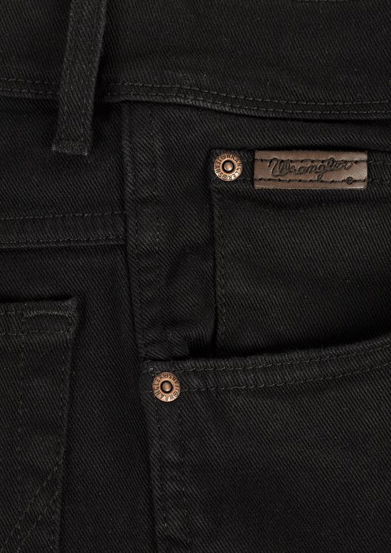 Detail van koperen Wrangler knopen en bruin logo label op zwarte jeans.