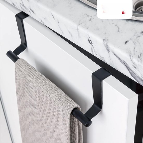 Porte-serviette noir avec un torchon beige gaufré, suspendu à une porte d'armoire de cuisine blanche avec un plan de travail en marbre.