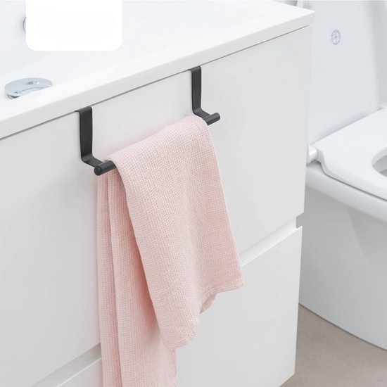 Porte-serviette noir avec un torchon rose pâle, suspendu à un meuble de salle de bain blanc avec des toilettes en arrière-plan.