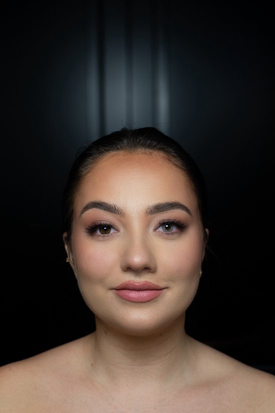 Close-up van een vrouw met één oog dat lichtgrijs is en het andere oog bruin. Ze draagt make-up en kijkt naar de camera.