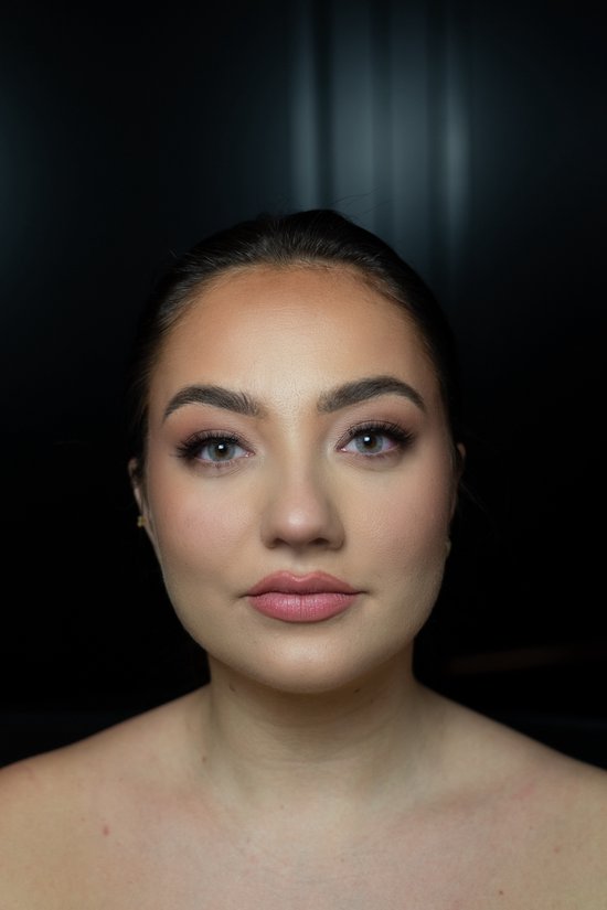 Close-up van een vrouw met blauwgrijze contactlenzen en make-up. Ze kijkt recht vooruit met een neutrale uitdrukking.
