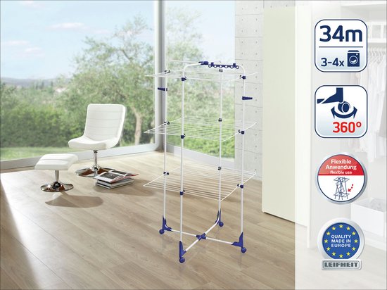 Wit met blauwe accenten, deze droogtoren heeft drie lagen droogrekken en staat in een lichte kamer naast een stoel.