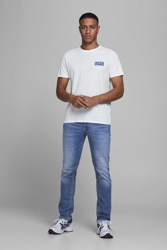 Man draagt een wit T-shirt met 'Jack & Jones' logo en lichte spijkerbroek.
