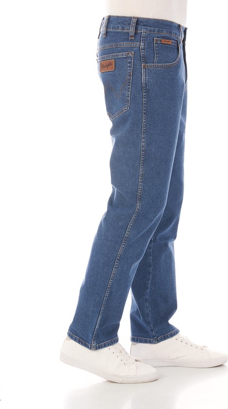 Blauwe Wrangler jeans, met bruin leren label op de zijkant en oranje stiksels.