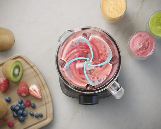 Bovenaf: Philips blender met draaiende rode smoothie. Fruit en glazen smoothies op tafel.