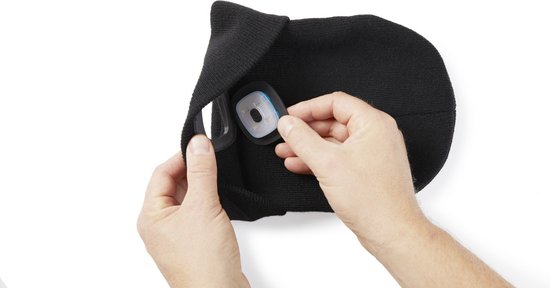 Zwarte beanie waarvan een hand het verwijderbare vierkante lampje uit de binnenzijde haalt.