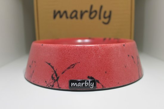 Rode marmeren voerbak met zwarte spetters en 'marbly' logo, op een witte ondergrond.