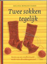 Boek 'Twee sokken tegelijk' met oranje gebreide sokken, wol en breinaalden.