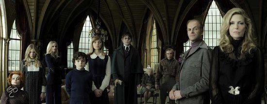 Groep mensen, waaronder Barnabas Collins met bleke huid, in een grote hal met gotische architectuur.