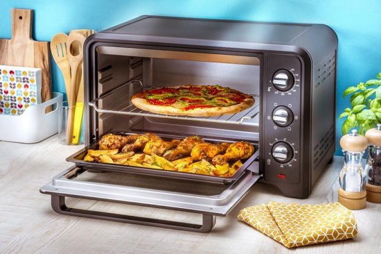 Zwarte mini-oven met een open deur. Oven bevat een pizza op het bovenste rek en kip met aardappelen op het onderste.