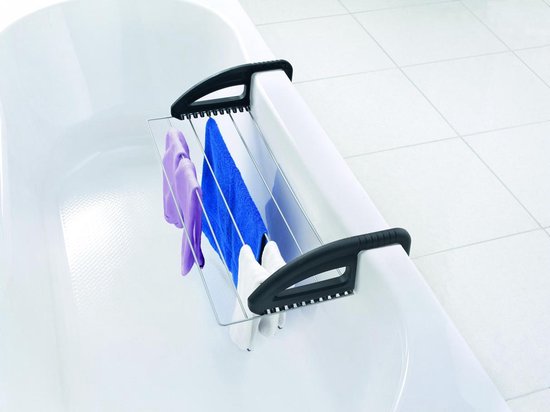 Een zilverkleurig droogrek met zwarte haken, bevestigd aan de rand van een wit bad, met paarse, blauwe en witte handdoeken eraan.