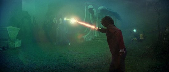 Harry Potter staat in een groen mistig kerkhof en vuurt een rode straal af op een Dementor.