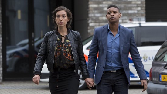 Man en vrouw, hand in hand, lopen naar camera. Vrouw draagt zwart jack.