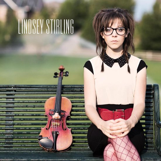 Lindsey Stirling met bril en vlechtjes zit op een bankje naast een viool. Ze draagt een rode riem en geruite kousen.
