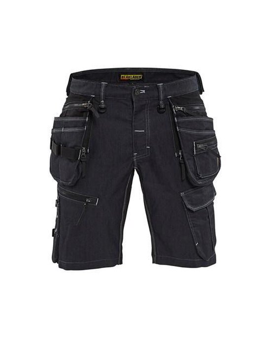 Zwarte spijker werkbroek met veel zakken, ritsen en witte stiksels.