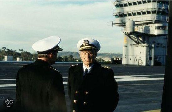 Twee marineofficieren in uniform op het dek van een vliegdekschip.