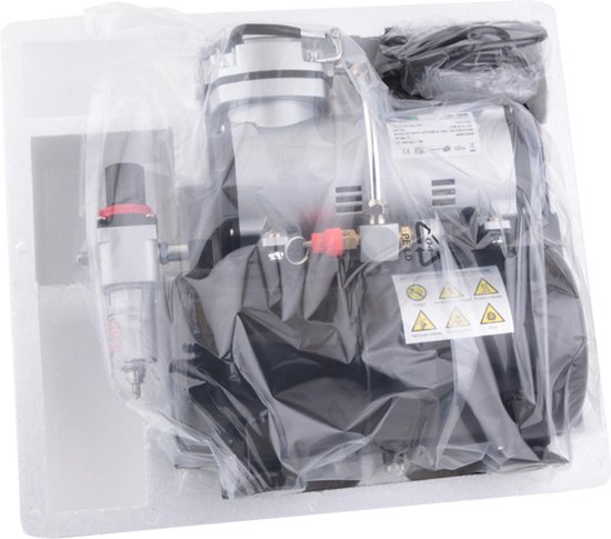 Airbrush compressor in plastic verpakking, zilver met zwart, met drukmeter en filter.