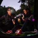 Man en vrouw zitten op een deken, man met hoofdlamp, vrouw met thermoskan.