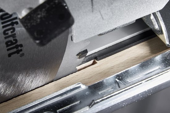 Close-up van een cirkelzaag die een groef in een houten plank zaagt.