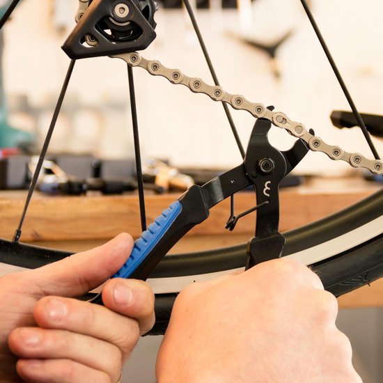 Personne utilisant une pince à chaîne bleue pour attacher une chaîne de vélo.