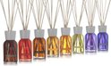 Rij van acht Millefiori Milano diffusers in diverse kleuren bruin, rood, oranje, geel en paars met witte doppen en stokjes.