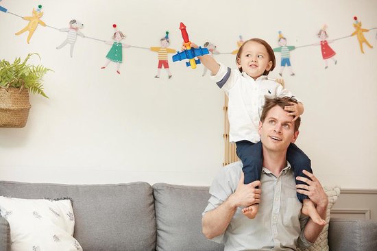 Vader draagt zoon op schouders, kind speelt met blauw en rood speelgoedvliegtuigje.
