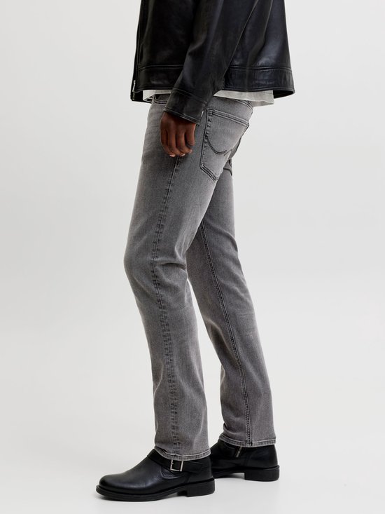 Detail van grijze jeans met zwarte laarzen.