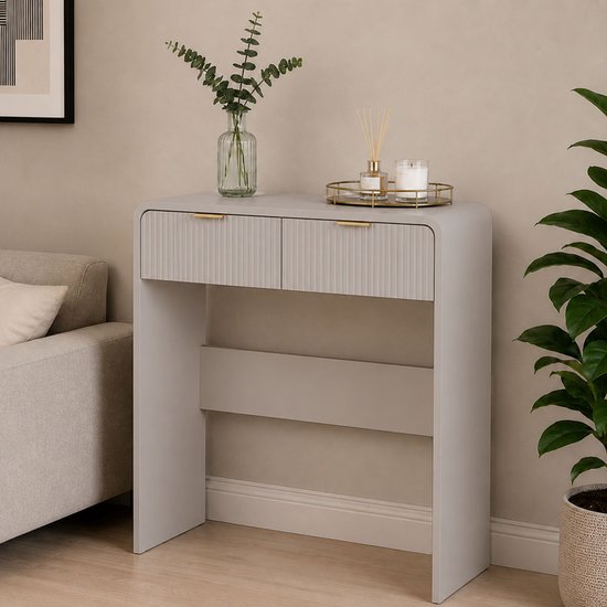 Crèmekleurige console tafel met twee geribbelde ladefronten en gouden handgrepen, naast een bank.