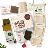 Geschenkset met verschillende soorten Aleppo zeep in groene en bruine tinten, een shampoo bar, een organzazakje en een zeepdispenser.