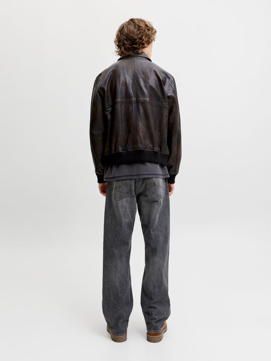 Model op de rug gezien in grijze jeans en donker jack.