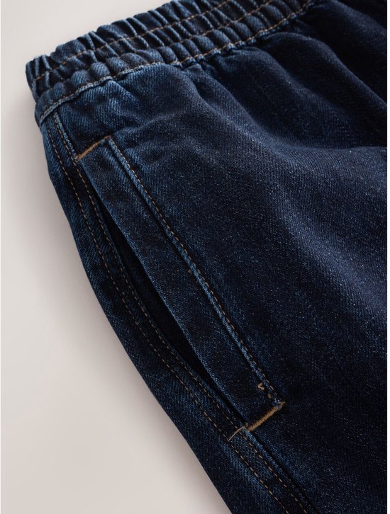 Detail van de zak en elastische tailleband op een donkerblauwe jeans.