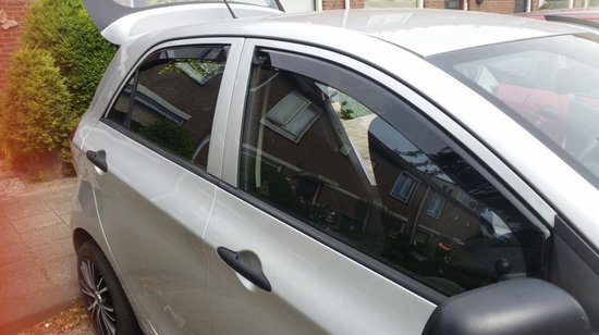 Zilveren auto met zwarte windschermen op de ramen.