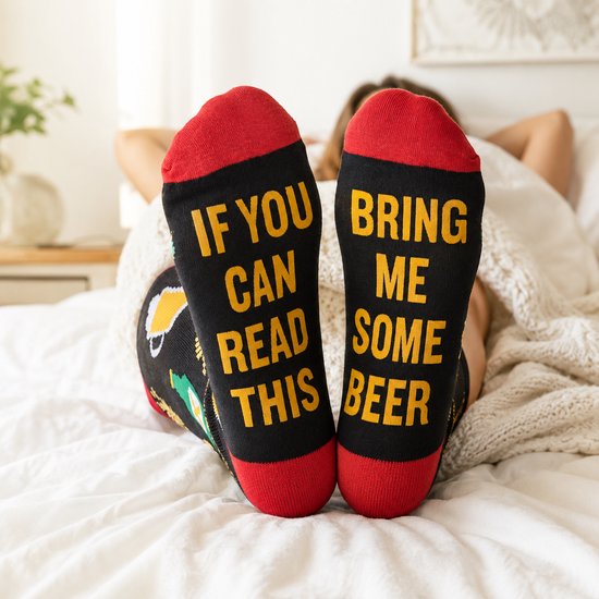 Voeten van een vrouw met zwarte sokken die tekst 'IF YOU CAN READ THIS BRING ME SOME BEER' tonen.
