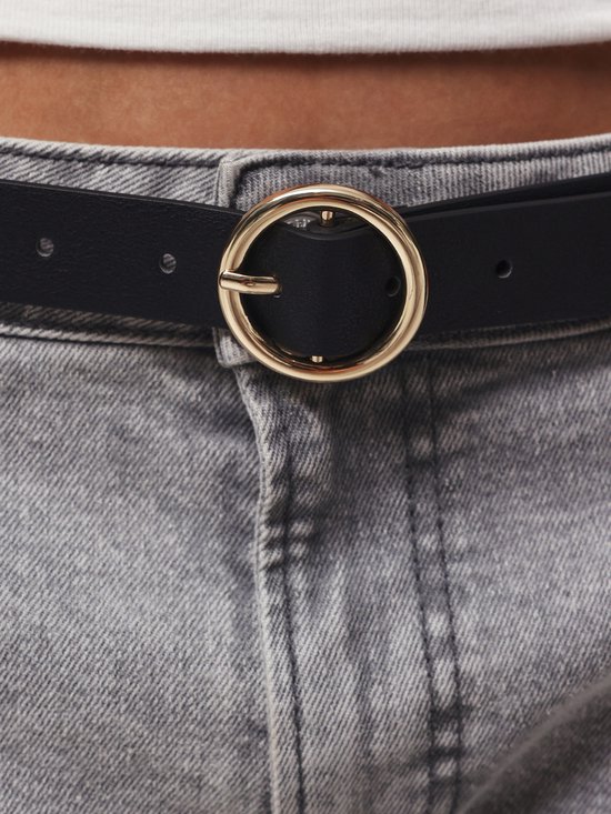 Zwarte riem met goudkleurige gesp, gedragen met een grijze spijkerbroek.
