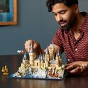Homme construisant un modèle LEGO du château de Poudlard avec voiture volante et bateau.