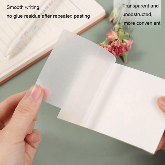 Handen houden een transparant memoblaadje vast bij een notitieboekje en gedroogde bloemen.