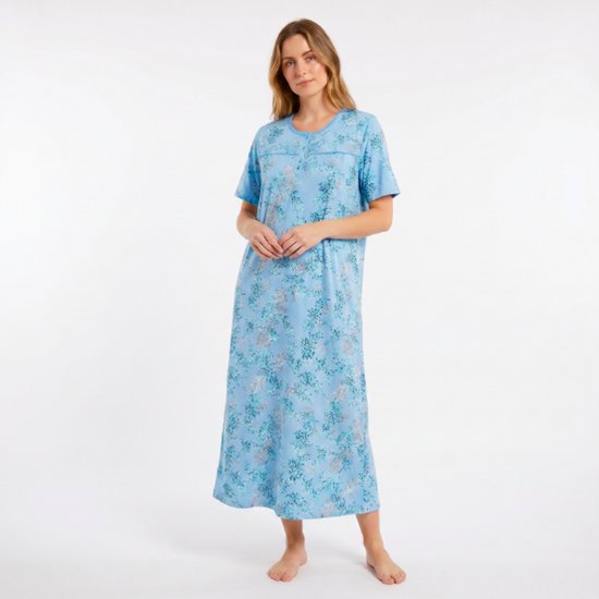 Model in een lichtblauwe nachtjapon met korte mouwen, een bloemenprint van blauwe en grijze bloemen en bladeren, en een ronde hals met knoopjes.