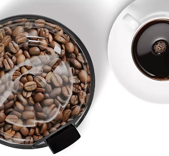 Zicht van bovenaf op een zwarte koffiemolen vol met koffiebonen, naast een kop koffie.