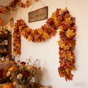 Herfstbladerenslinger hangend aan een muur met een bord en bloemen.