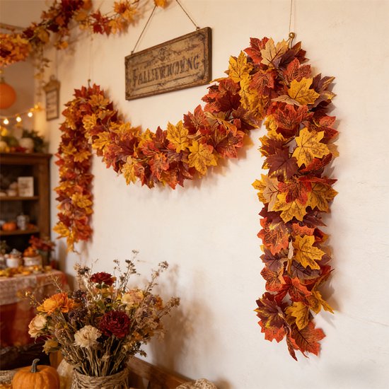 Herfstbladerenslinger hangend aan een muur met een bord en bloemen.