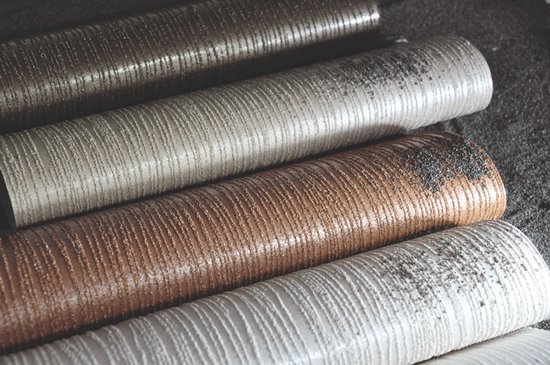Verschillende rollen vliesbehang met verticale zandkorrel structuur in de kleuren wit, taupe, brons en zilver.
