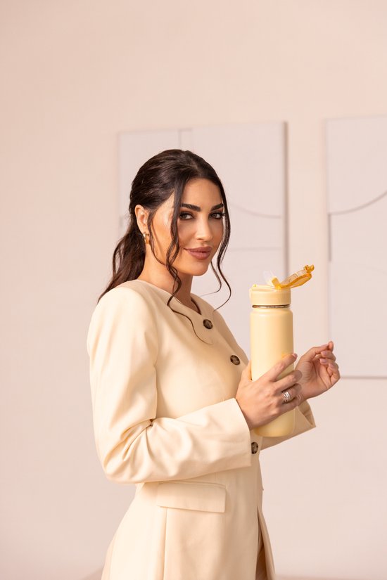 Vrouw met donker haar in een lichtgele blazer, houdt een lichtgele CABAU waterfles vast.