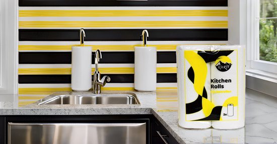 Kurtt keukenrollen verpakking in een moderne keuken, met zwart, geel en witte strepen achter de gootsteen.