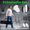 Fotostudio set met man, draagtas, afstandsbedieningen, paraplu's, lampen, softbox en statieven.