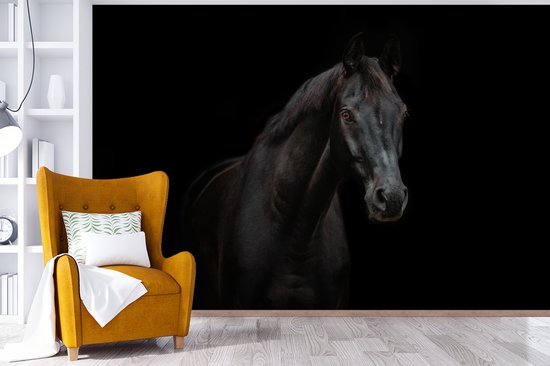 Woonkamer met fotobehang van een zwart paard achter een gele fauteuil met een wit kussen.