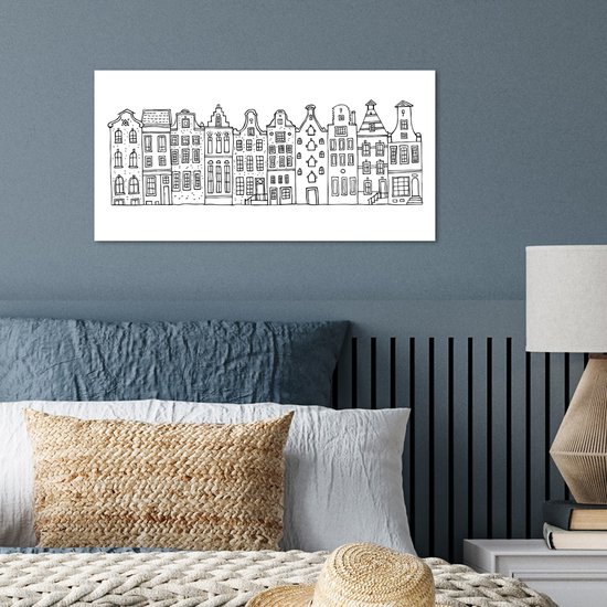 Zwart-wit poster met Amsterdamse huisjes, boven een bed met kussens.