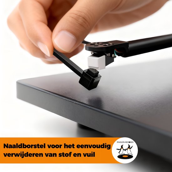 Hand reinigt de naald van de platenspeler met het zwarte borsteltje.