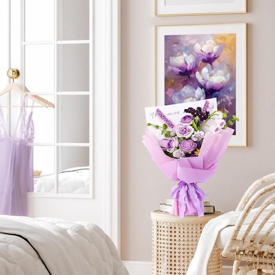 Paars gehaakt boeket met rozen en lavendel, gepresenteerd op een nachtkastje naast een schilderij met paarse bloemen.
