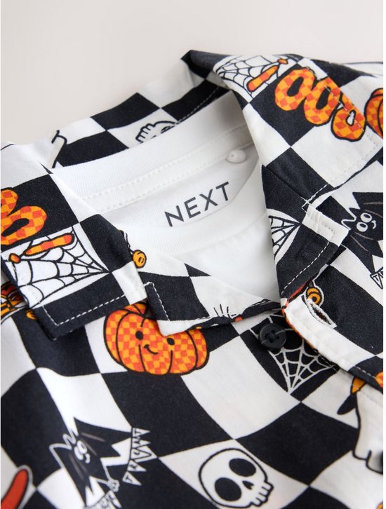 Close-up van de kraag van het Halloween-overhemd met het 'NEXT' label op het onderliggende witte T-shirt.
