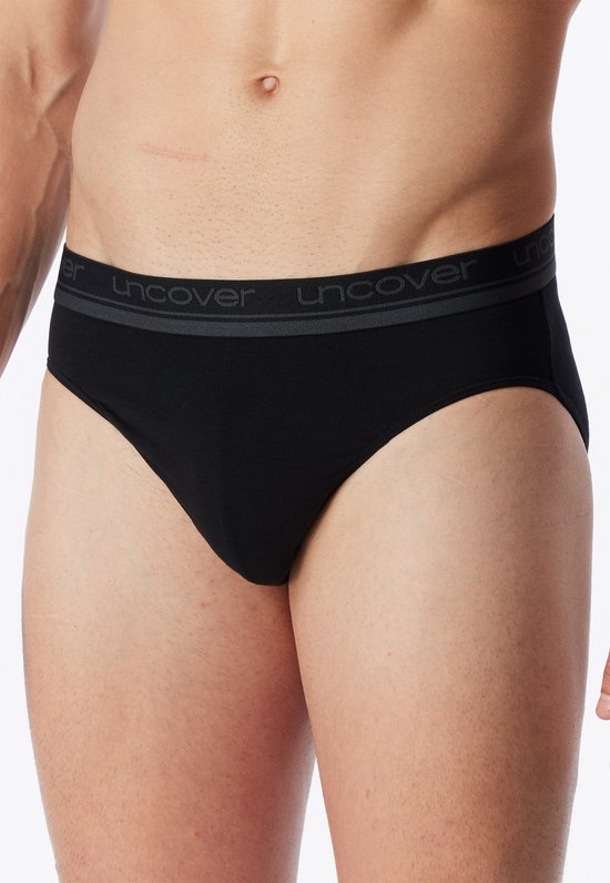Man draagt zwarte slip met grijze band met UNCOVER-logo.